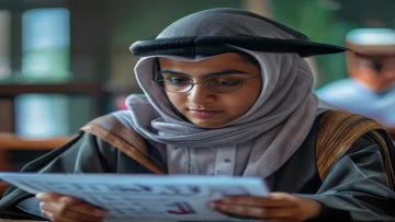 A determined Saudi student looking at their academic results on a tablet with a graduation