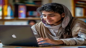 A student looking relieved and accomplished while using a laptop displaying the Madrasati