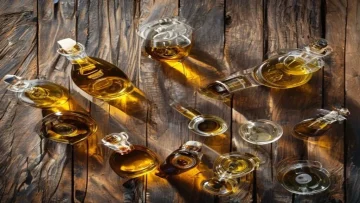 An overhead shot of a rustic wooden table filled with various glass bottles of olive oil f