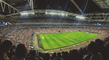 Football stadium with bright lights passionate fans in the stands and a soccer ball on the